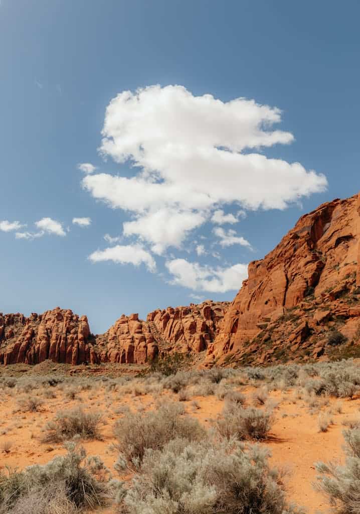 A desert landscape with red rocks and clouds