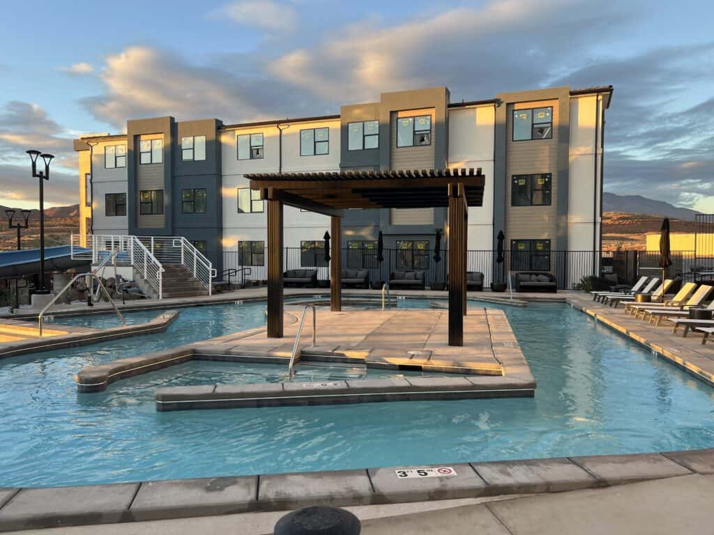 Modern apartment complex with outdoor pool at sunset.