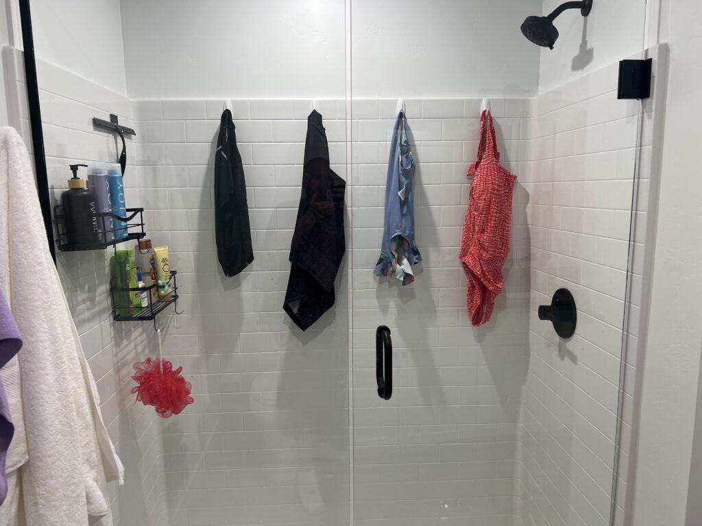 Shower with towels and toiletries on shelves.