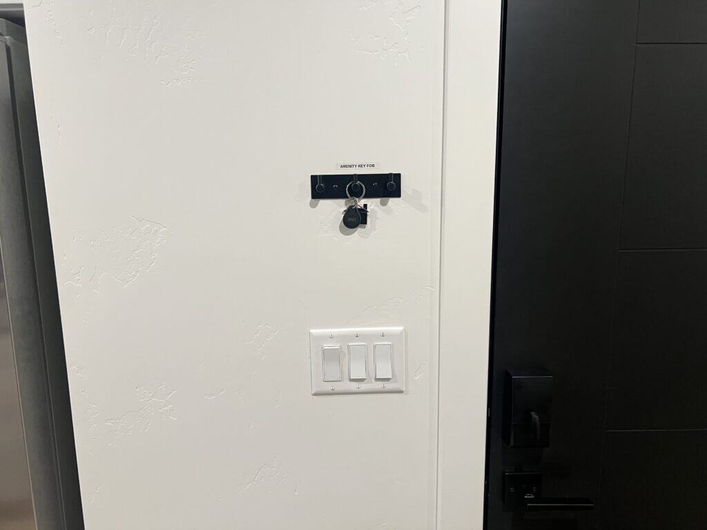 Key fob hanging on white wall near switches.