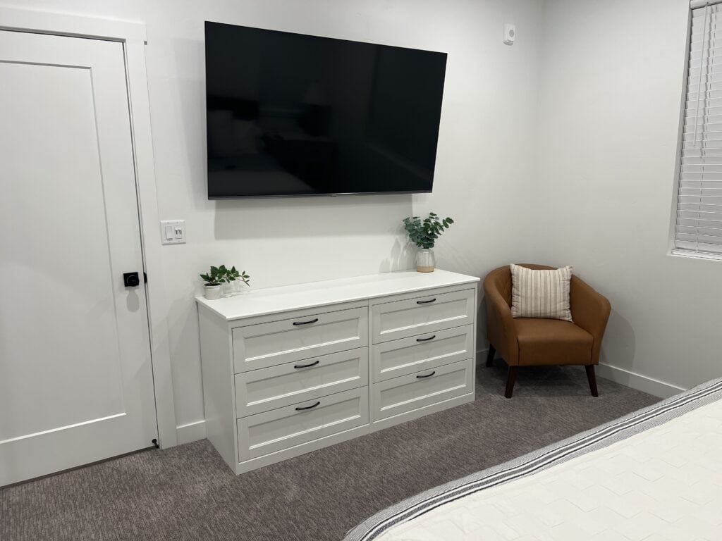 Modern bedroom with TV, dresser, and chair