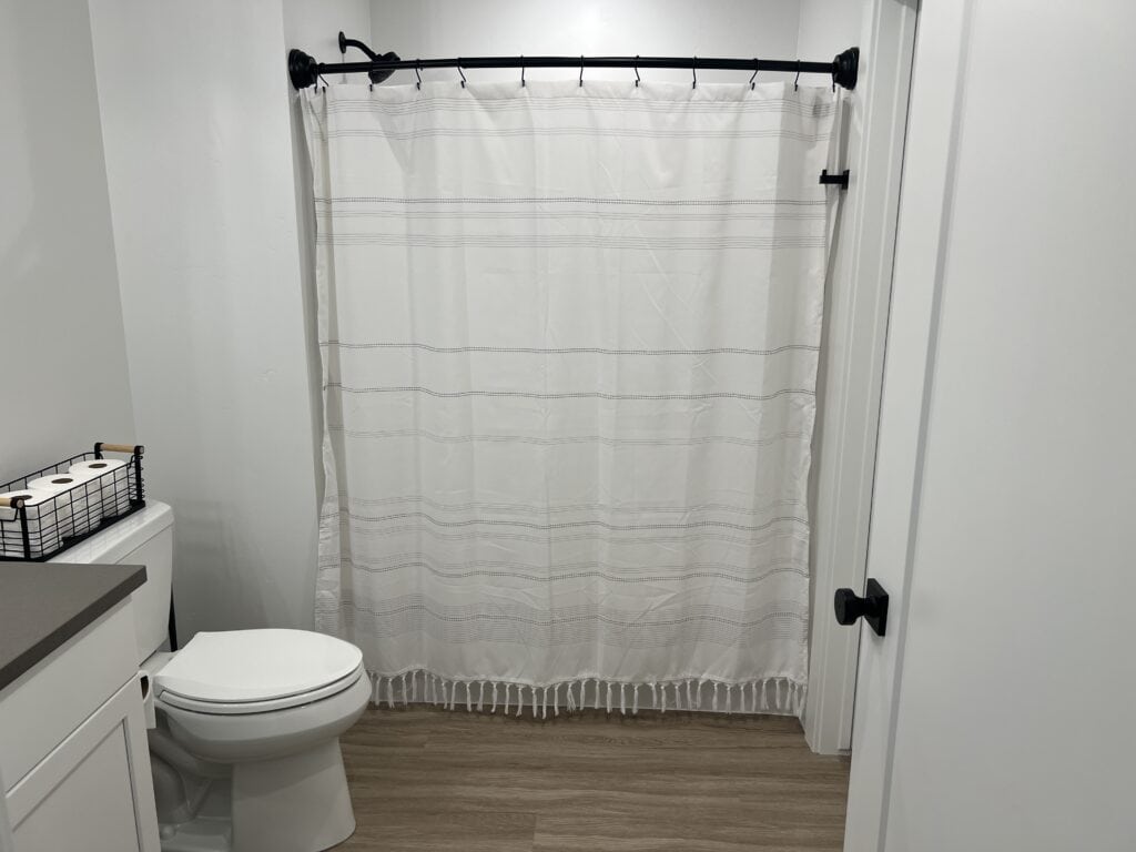 Modern bathroom with shower curtain and toilet paper.