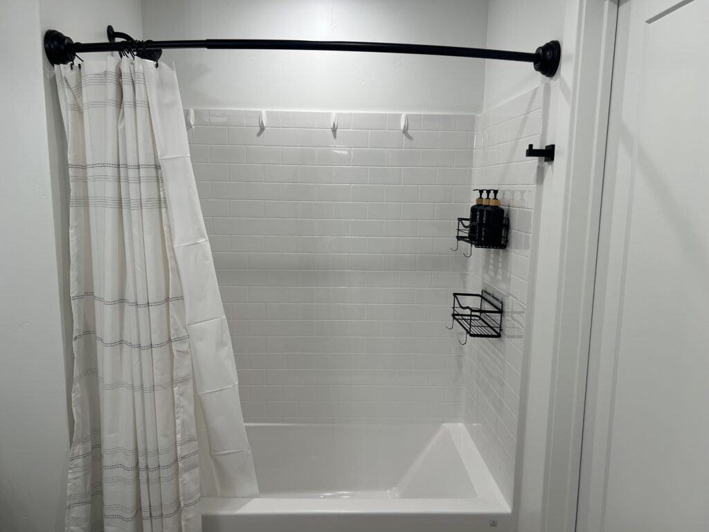 White shower with curtain and wall-mounted shelves.