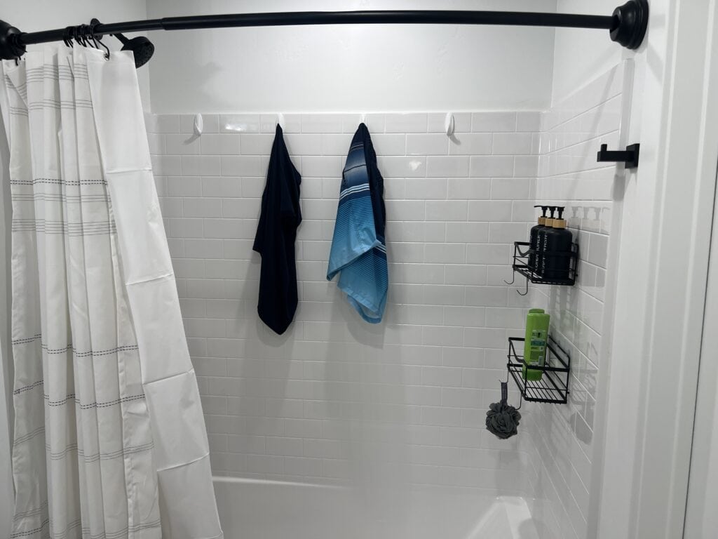 Bathroom shower with curtain and toiletries on shelves.