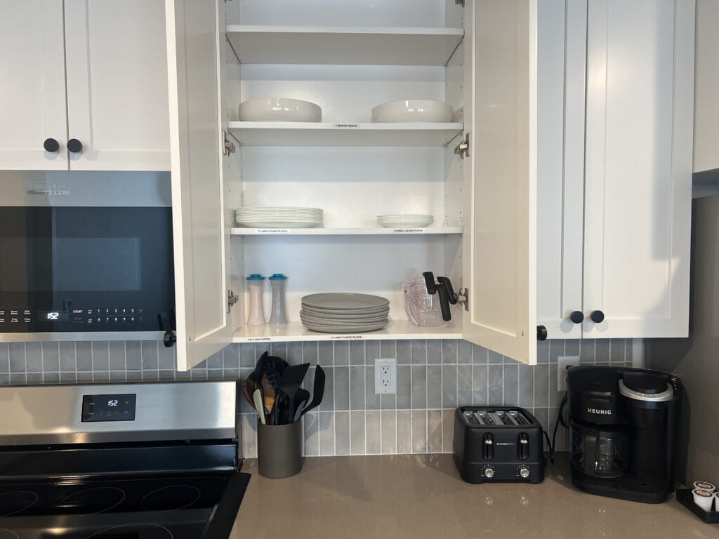 Kitchen cabinets open with plates and appliances visible.