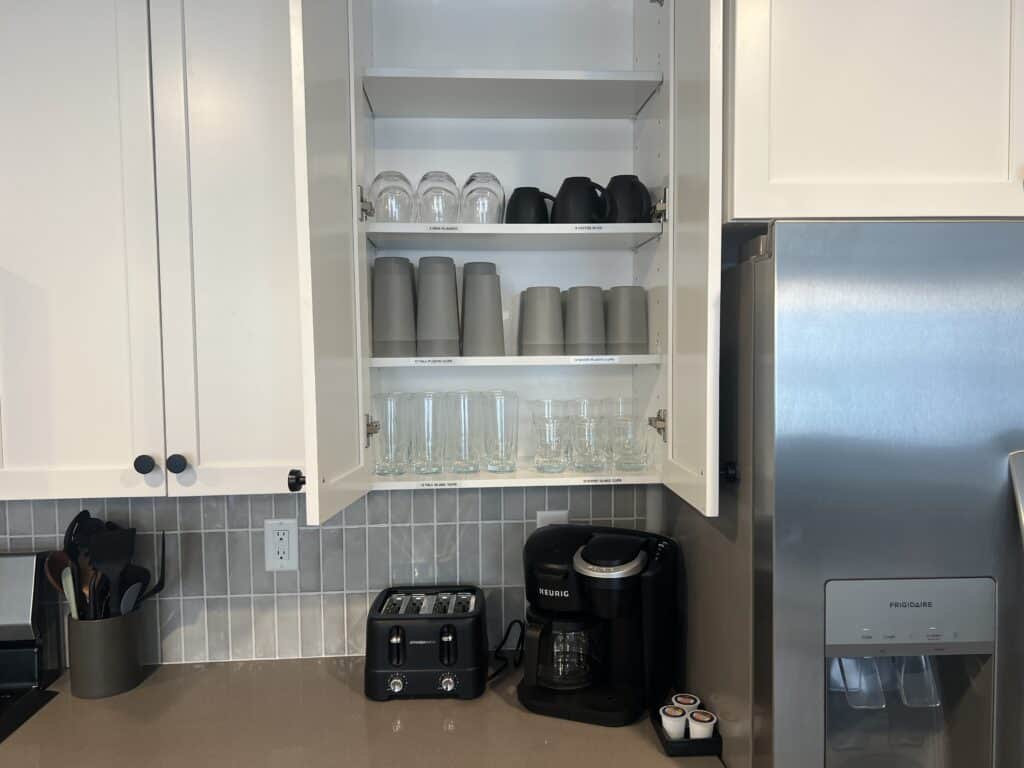 Open kitchen cabinet with glasses and mugs.