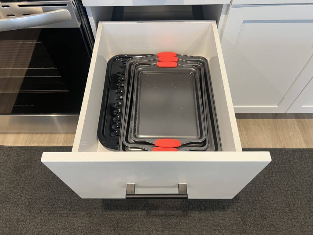 Drawer with baking trays and red handles.