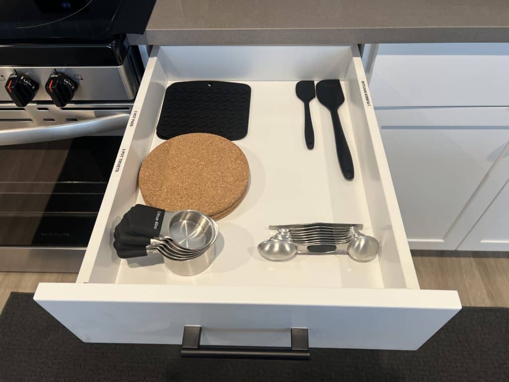 Open kitchen drawer with utensils and measuring cups