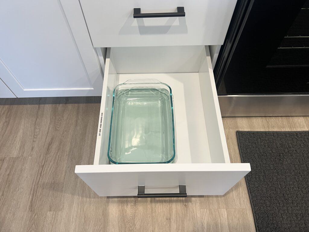 Open kitchen drawer with glass baking dish inside.