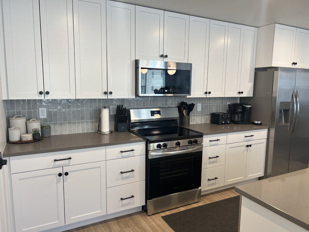 Modern kitchen with white cabinets and stainless appliances.