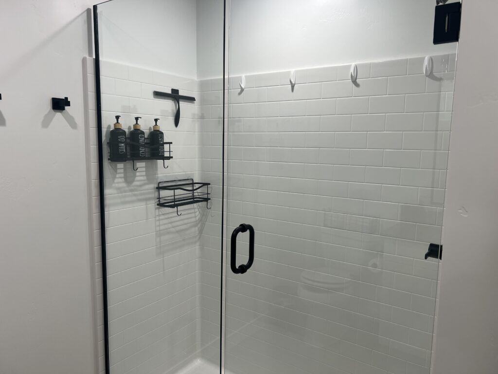 Modern glass shower with wall-mounted soap dispensers.