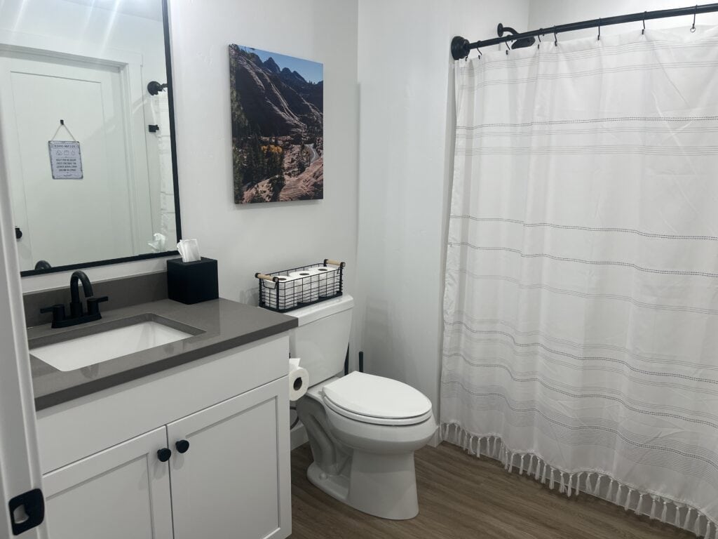 Modern bathroom with white decor and mountain photo.