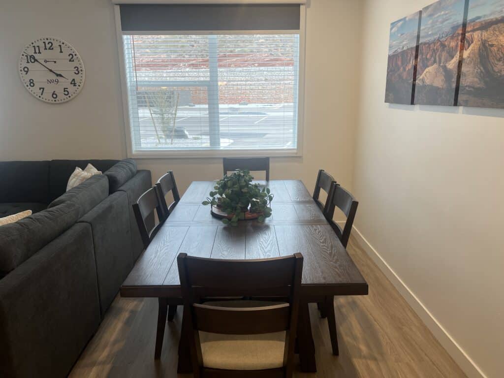 Dining room with table, plants, and clock.